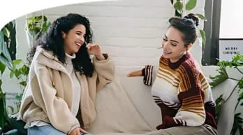 Two women having a discussion on a couch.