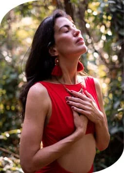 A woman in a red dress standing in a serene forest.