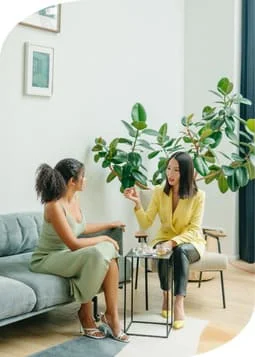 Two women engaged in conversation while seated on a couch.