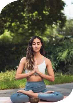 Woman in yoga pose holding a cup of water.